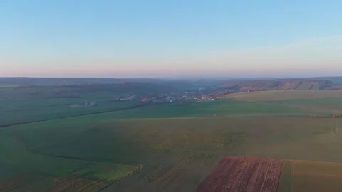 Expansive agricultural fields and a small village in the rolling countryside of Stock Footage 346721534
