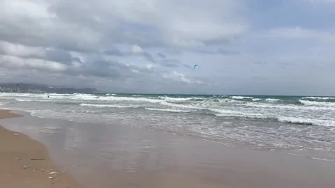 Expansive beach scene with flying kites and waves. Wide sandy coast featuring Stock Footage 327915769