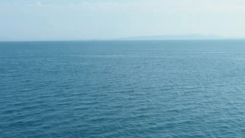 Expansive blue ocean horizon with distant hazy mountains and clear sky Vidéo 331278184
