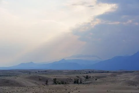 Expansive desert dunes under a dramatic sky with distant mountains Stock Photos