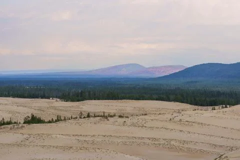 Expansive desert dunes under a dramatic sky with distant mountains Foto stock