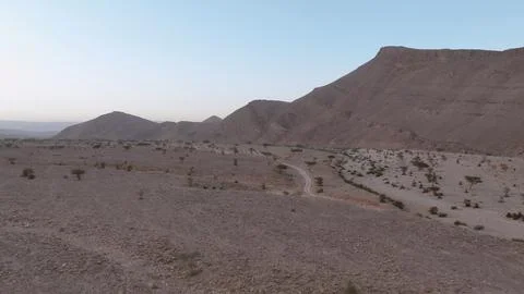 Expansive Desert Plain with Dirt Tracks and Mountain Range at Dawn Stock Photos