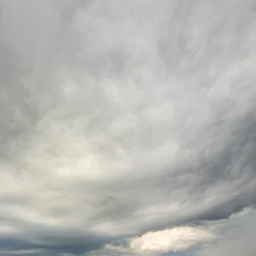 Expansive dramatic overcast sky filled with swirling grey white clouds. Stock Photos