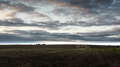 Expansive Field Landscape Under a Cloudy Sky During Sunset Stockbeeldmateriaal 315366823