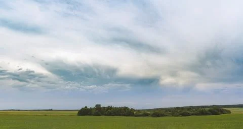 Expansive green fields under dramatic summer clouds 写真素材