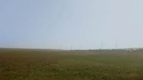 Expansive hazy meadow with distant power lines seen from train. Vast and Stock-Footage 323913971