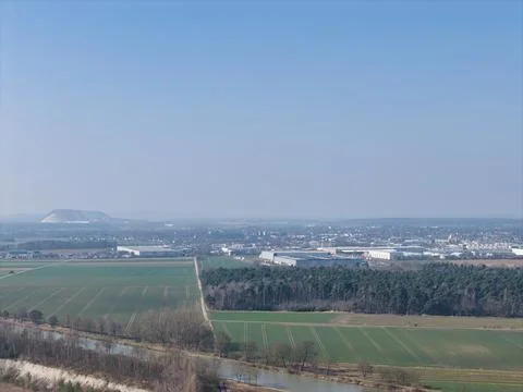 An expansive landscape featuring vast fields alongside a bustling industrial Stock Photos