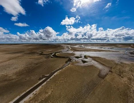 Expansive marshland features meandering streams beautifully flowing under d.. Stock Photos