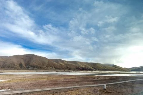 Expansive mountain landscape under a dramatic cloudy sky. A river flows acr.. 库存照片