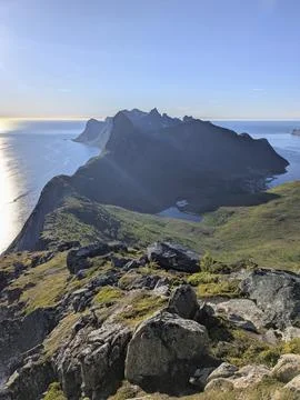 Expansive mountain range extending into the ocean under warm sunlight with a Stock Photos