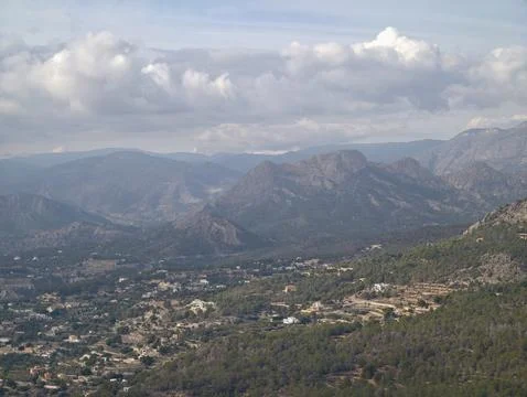 Expansive mountain range under soft blue sky featuring scattered clouds and.. Photos