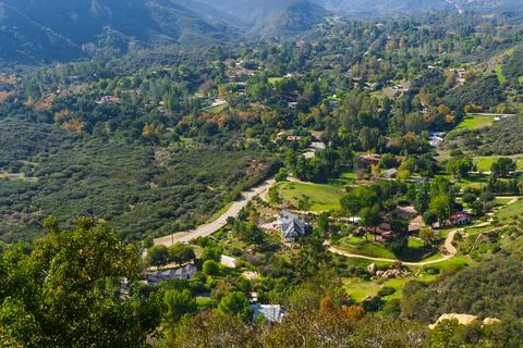 Expansive Mountainous Valley With Winding Road And Scattered Residences Stock-Fotos