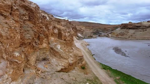 Expansive River Valley with Winding Dirt Road and Prayer Flags Tibet China Stock Footage 346586780