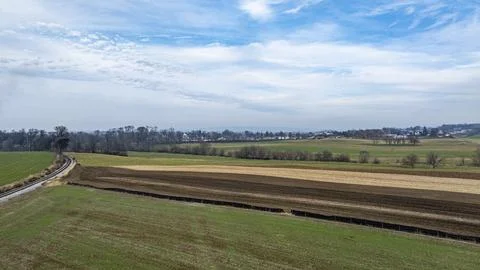 Expansive Rural Landscape Showcasing Fields and a Winding Road Under a Clou.. Stock Photos