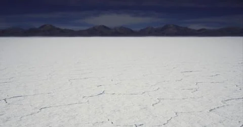 Expansive salt flats under a dramatic sky near mountains Stock Illustration