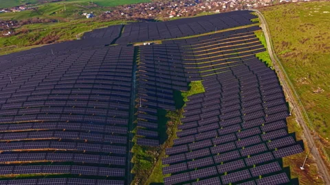 Expansive solar panel array captures sunlight in rolling green hills under a Stock Footage 336624981