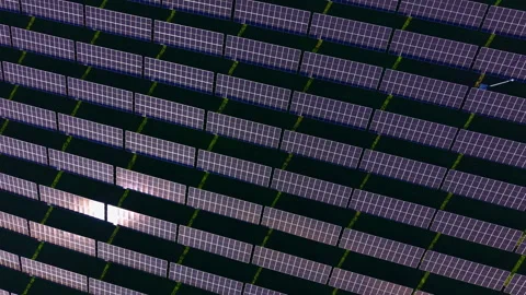 Expansive solar panel array capturing sunlight across a green landscape under a Stock Footage 331947446
