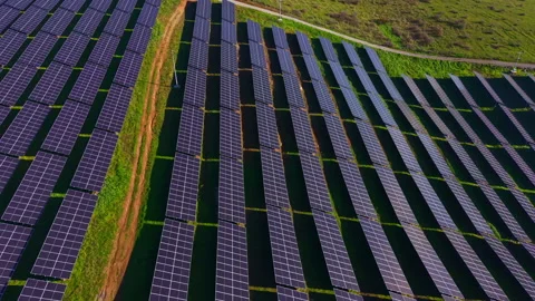 Expansive solar panel array shining under the bright sun in a lush green field, Stock Footage 332027669