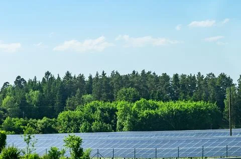 Expansive solar panel farm under a clear blue sky with fluffy clouds and lu.. Стоковые фото