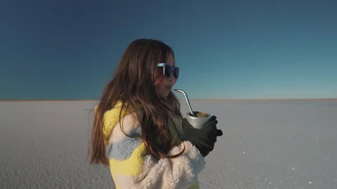 Expansive static frames girl savoring traditional mate on shimmering Salinas Stock Footage 327271305