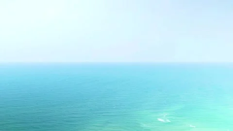 Expansive turquoise waters blending seamlessly with cloudless pale blue horizon Stock Footage 307939424