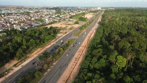 Expansive urban arterial cuts through lush forest canopy adjacent to growin.. Vidéo 339040430