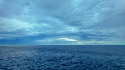 Expansive view of calm ocean under a cloud-laden sky with varying shades of blue Stock Footage 317328697