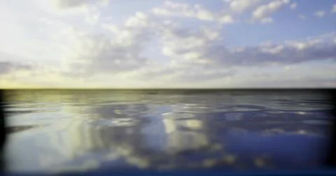 Expansive view of calm water reflecting a colorful sky at sunset Stock Illustration