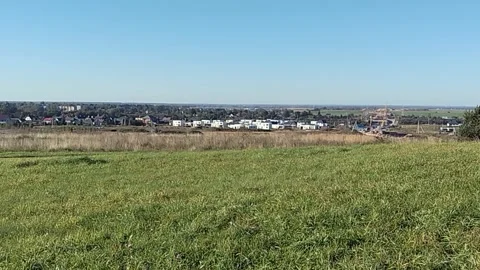 Expansive view of a grassy hill overlooking a developing suburban area with Stock Footage 332144731