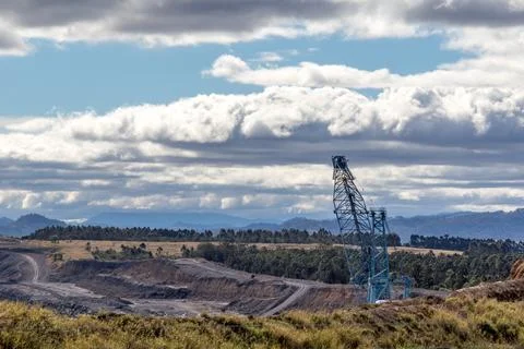 Expansive view of an open-cut coal mine with a large excavator working Stock Photos