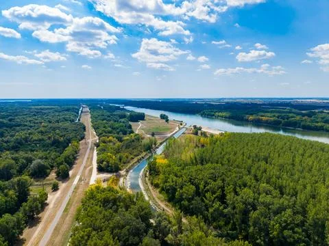 Expansive view of a river and fields surrounded by trees under a blue sky w.. Stock Photos