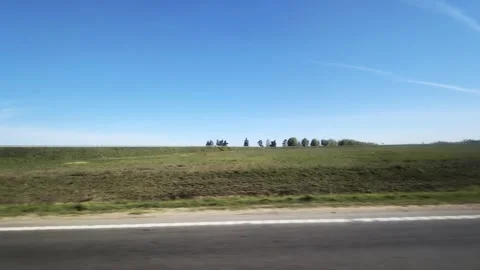 Expansive view of rural landscape from moving car with winding road, vast green Stock Footage 344095559