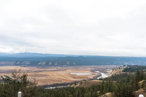 Expansive vista: River meanders through a valley on a cloudy day Stock Photos