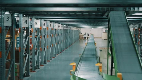 Expansive warehouse aisle with numbered shelving and a roller conveyor inside an Vídeos de archivo 335861576