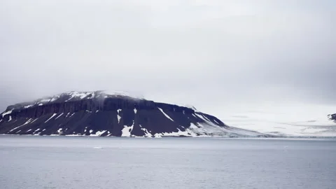 Expansive wintry scene showcasing rugged snow-dusted mountains partially Video stock 312208300