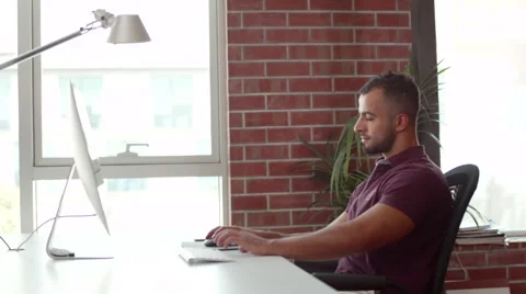 Expat businessman using computer and messaging on mobile at office. Stock Footage 64101319