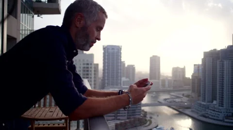 Expat man messaging on mobile at balcony. Stock Footage 62427133