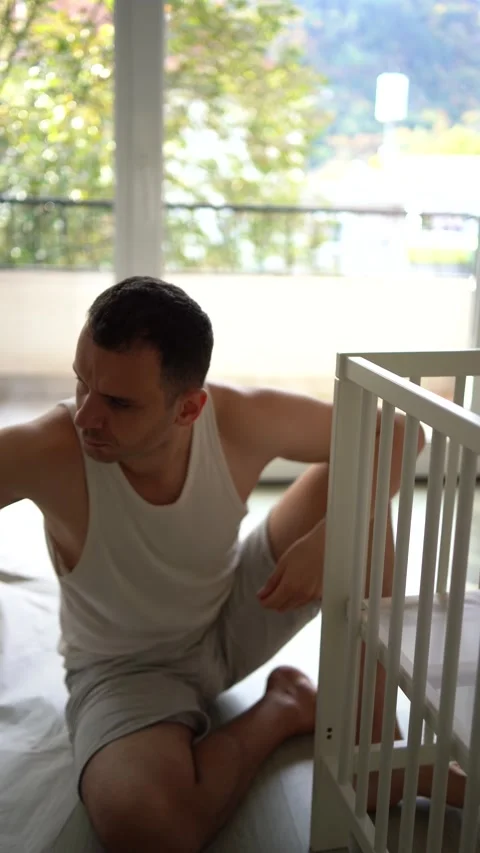 Expectant father preparing a nursery by assembling a wooden crib Stock Footage 329486396