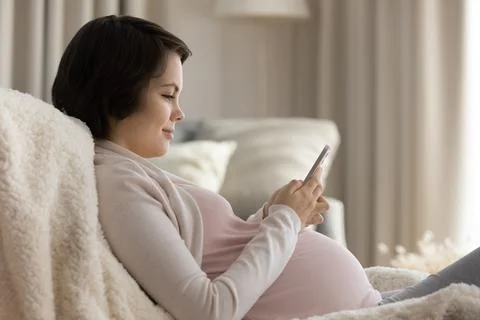 Expectant mom watch childbirth video on phone text message Stock Photos