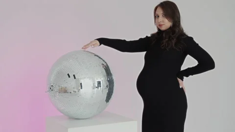 Expectant mother with bright makeup rotates mirror sphere and looks at camera Stock Footage 169794427
