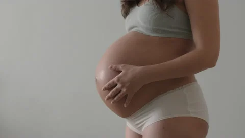 Expectant mother gently put her hands on pregnant belly and stroks it with love Stock Footage 169361408