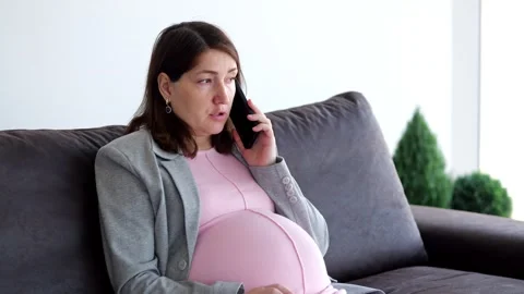 Expectant mother sits on couch talking during remote job Stock Footage 309667930