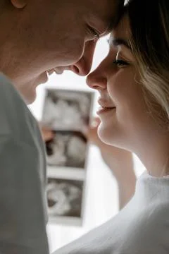 Expectant parents touch foreheads while holding an ultrasound scan. The scene Stock Photos
