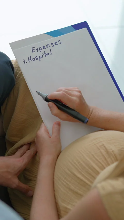 Expecting couple sitting on the couch discussing future baby expenses. Stock Footage 332660316