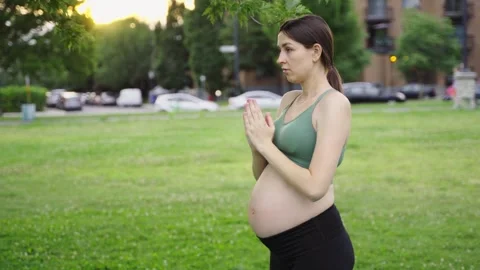 Expecting female in park doing yoga in her third trimester. Stock Footage 244411094