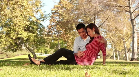 Expecting Interracial Couple sitting in Grass 2 Stock Footage 50233710