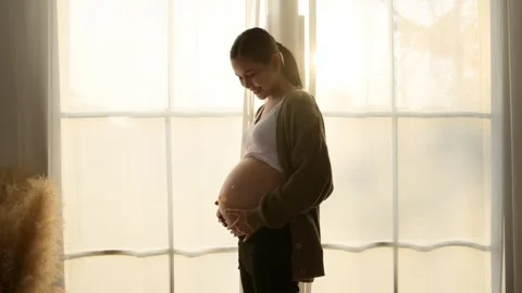 Expecting Joy During Soft Morning Light in a Cozy Indoor Stock Footage 296236676