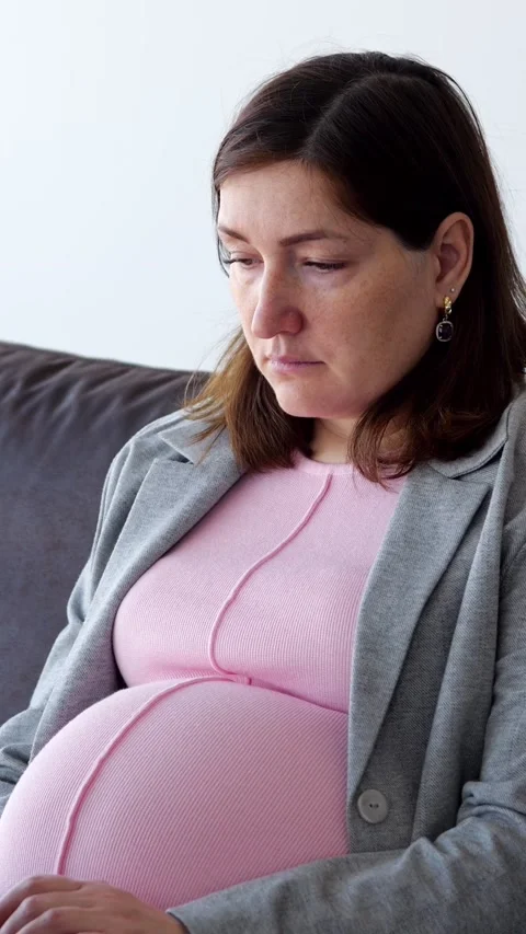 Expecting Mother Relaxes On Sofa While Considering Maternity Healthcare Advice Stock Footage 347194695