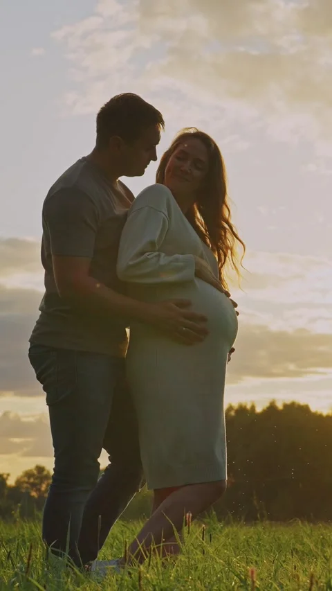 Expecting parents enjoying a sunset stroll in a serene field Stock Footage 288921786