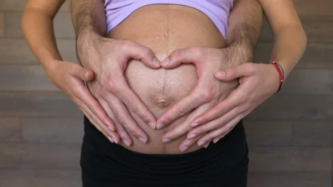 Expecting parents form a heart with hands on pregnant woman belly, close up Stock Footage 164719244